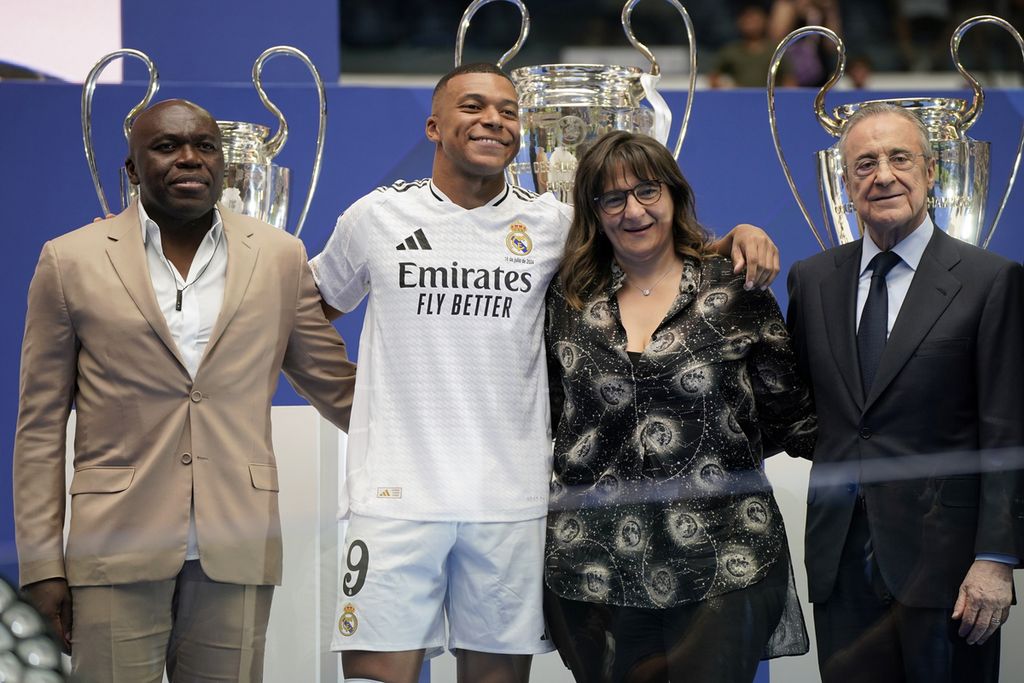 Kylian Mbappe berpose dengan kedua orangtuanya dan Presiden Real Madrid Florentino Perez (kanan) saat acara perkenalan di Santiago Bernabeu, Madrid, Selasa (16/7/2024).